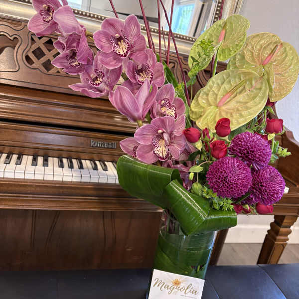Pink orchids and magenta blooms in a glass vase with green wrap