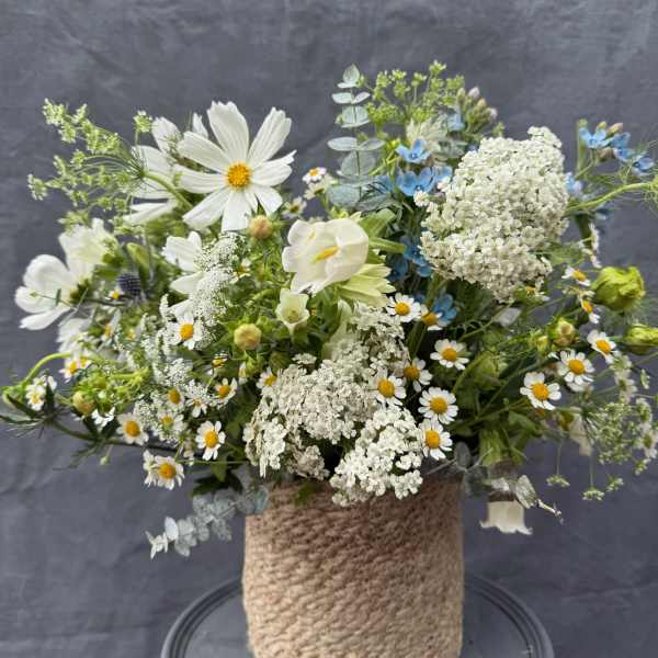Mixed white and blue flowers arranged in a rope-wrapped vase