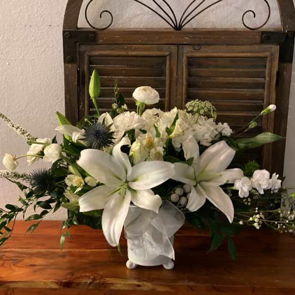 White lily and mixed white floral arrangement in a ceramic vase