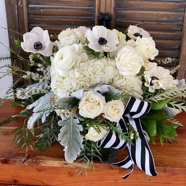 White floral bouquet with a black-and-white striped ribbon