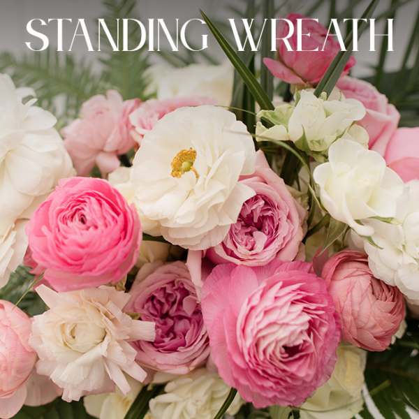 Pink and white standing wreath with layered blooms and palm fronds