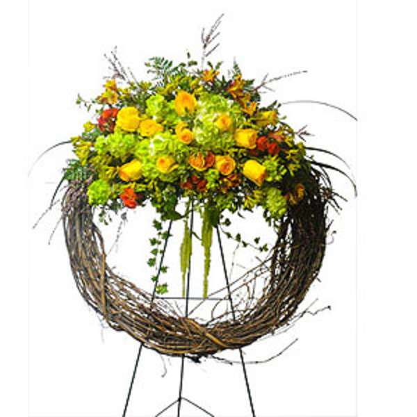 Yellow and orange floral arrangement in a twig wreath stand
