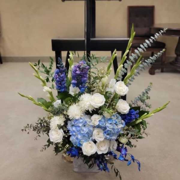 Blue and white floral arrangement with tall stems in a vase