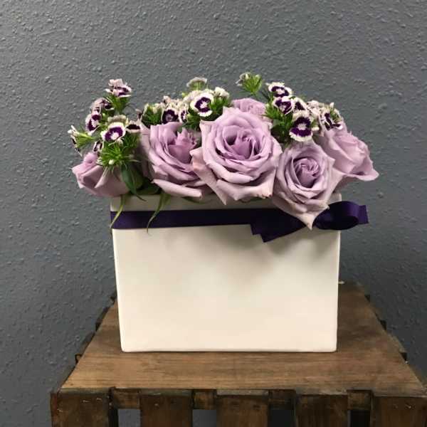 Lavender roses arranged in a white box with purple ribbon