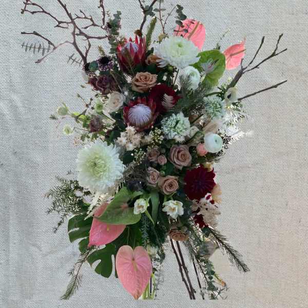 Tall floral arrangement with pink, white, and burgundy blooms