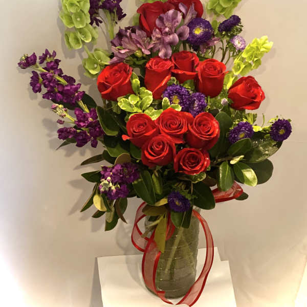Bouquet of red roses and purple flowers in a glass vase