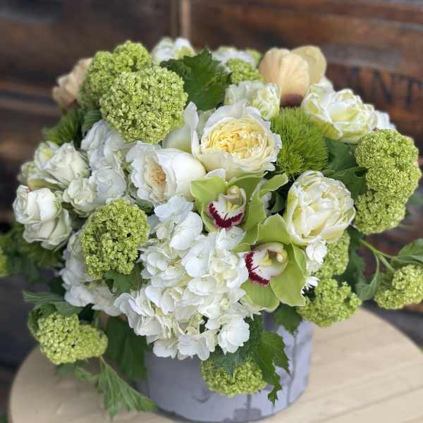 White and green floral arrangement in a round box