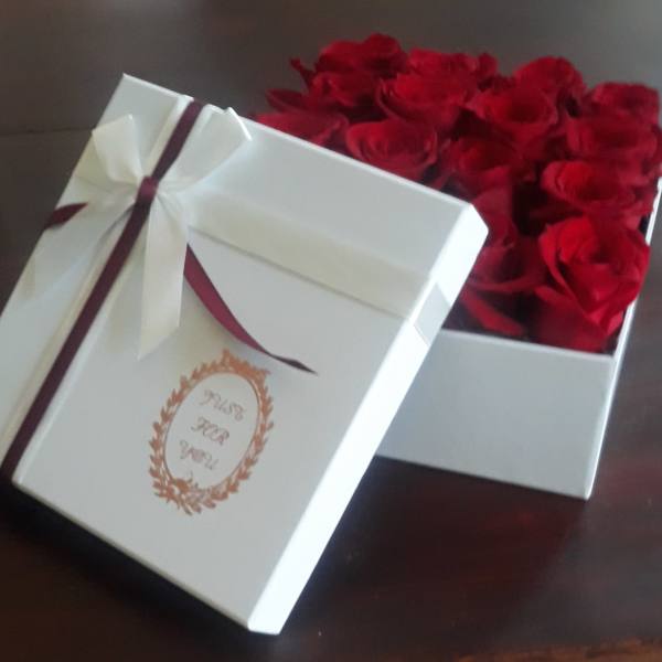 White gift box filled with red roses and tied with a ribbon