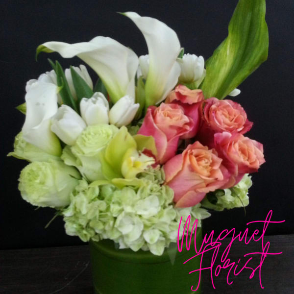Bouquet of white calla lilies, pink roses, and pale green hydrangeas in a green vase