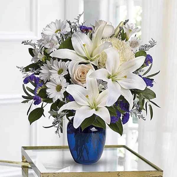 White lilies and daisies in a blue glass vase