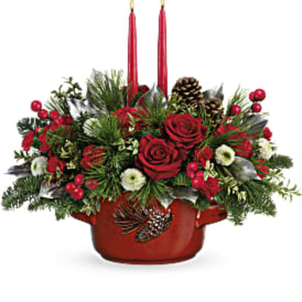 Red roses and holiday greenery in a red container with two red candles