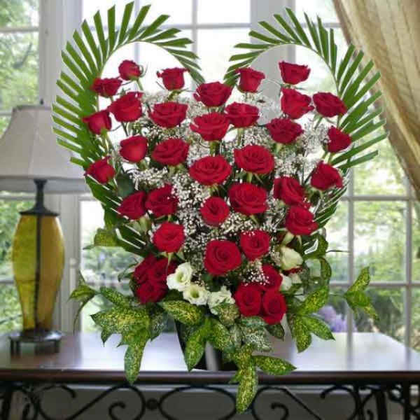 Heart-shaped bouquet of red roses with white filler flowers