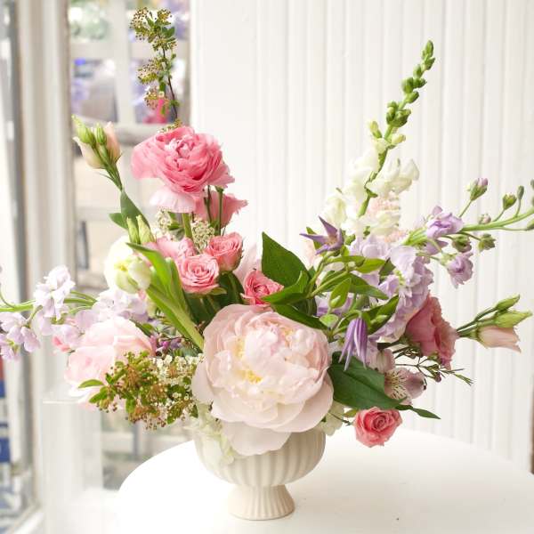 Pastel floral arrangement in a white pedestal vase