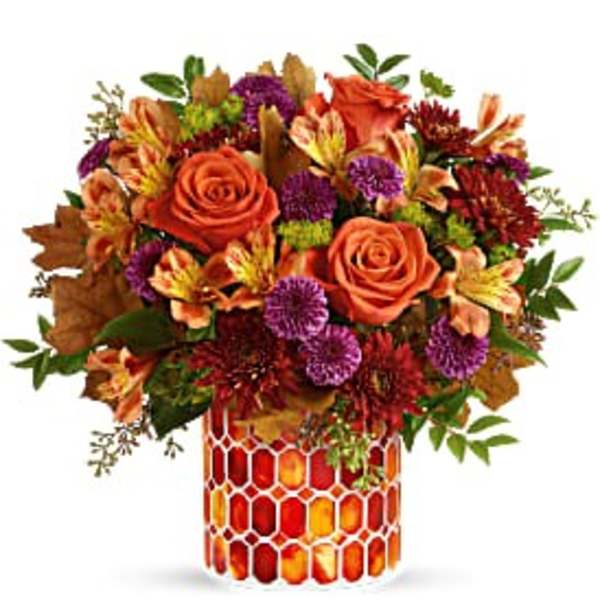 Orange roses and mixed fall flowers in a patterned vase