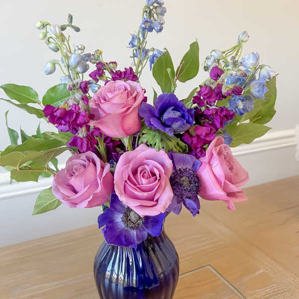 Pink and purple flower bouquet in a dark glass vase
