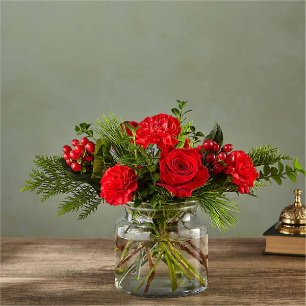 Red roses and carnations in a clear glass vase with greenery