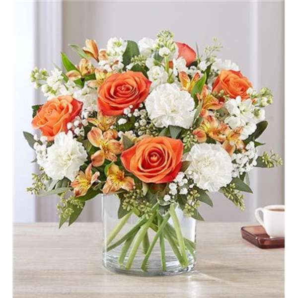 Orange roses and white carnations in a clear glass vase