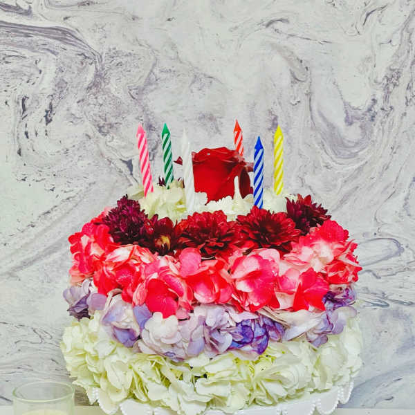 Round flower cake with colorful blooms and striped candles
