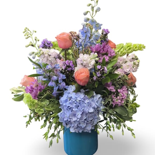 Mixed bouquet of blue, purple, pink, and white flowers in a blue vase