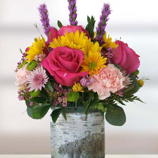Pink roses and yellow daisies in a glass vase