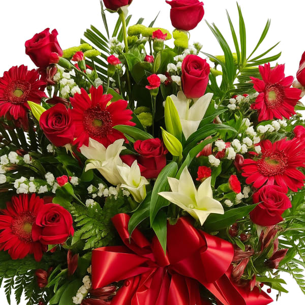 Red roses and gerbera daisies with white lilies and a red ribbon bow
