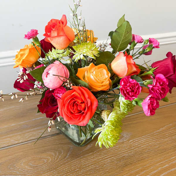 Mixed bouquet of roses, carnations, and mums in a glass vase