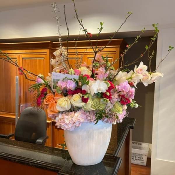 Large mixed floral arrangement in a white vase with tall branches