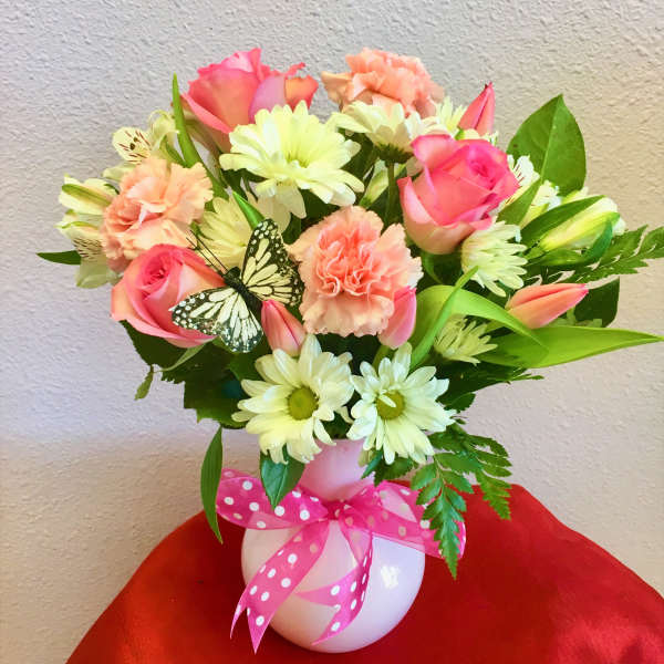 Pink and peach mixed bouquet in a white vase with a polka-dot ribbon