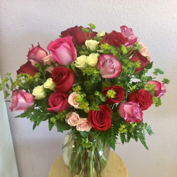 Mixed roses in pink, red, and cream arranged in a glass vase
