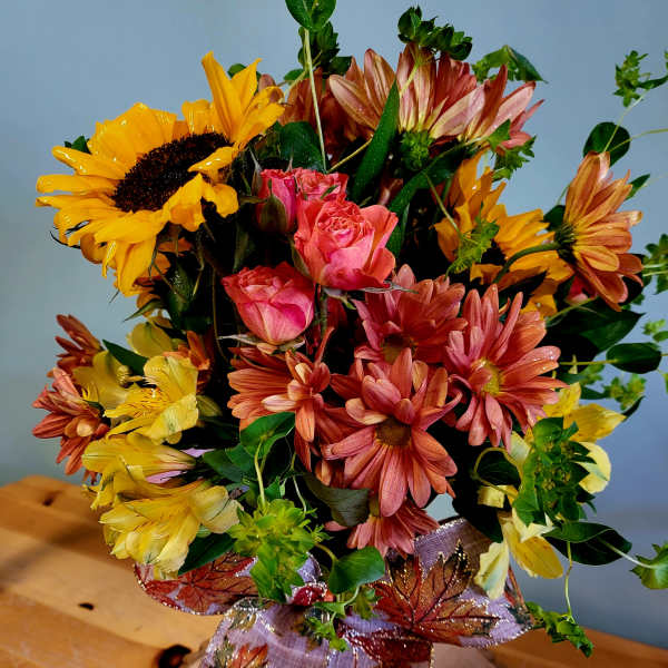Bouquet of sunflowers, pink roses, and daisies with a decorative ribbon