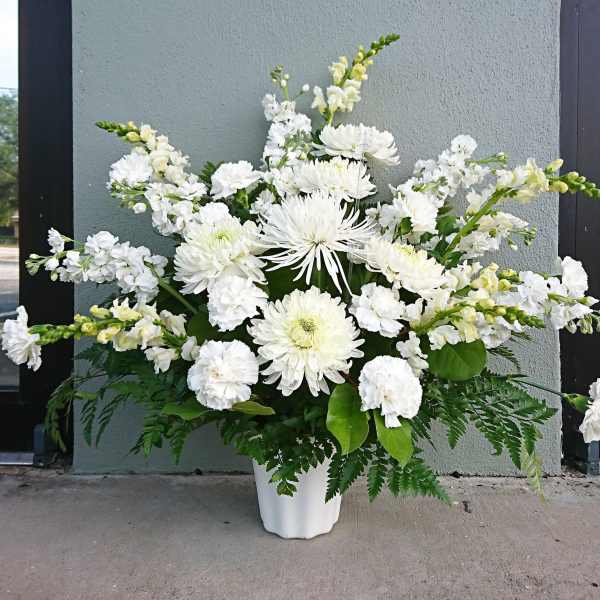 White floral arrangement in a white vase with mixed blooms and greenery