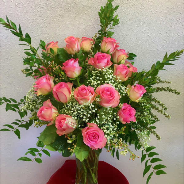 Pink roses arranged in a clear glass vase with white filler flowers