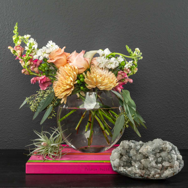 Peach roses and pale yellow chrysanthemums in a clear glass vase