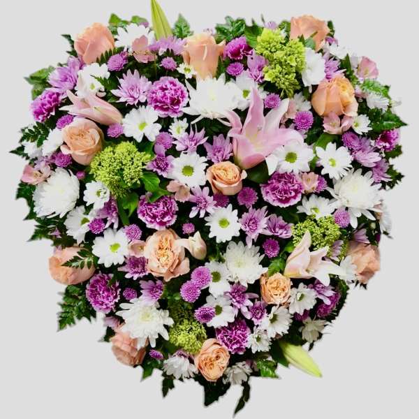 Heart-shaped floral arrangement with pink, white, and peach blooms