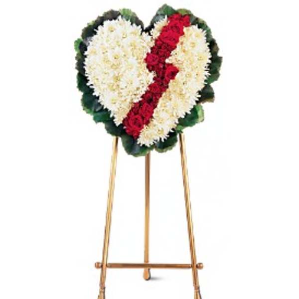 Heart-shaped funeral wreath of white and red flowers on a stand