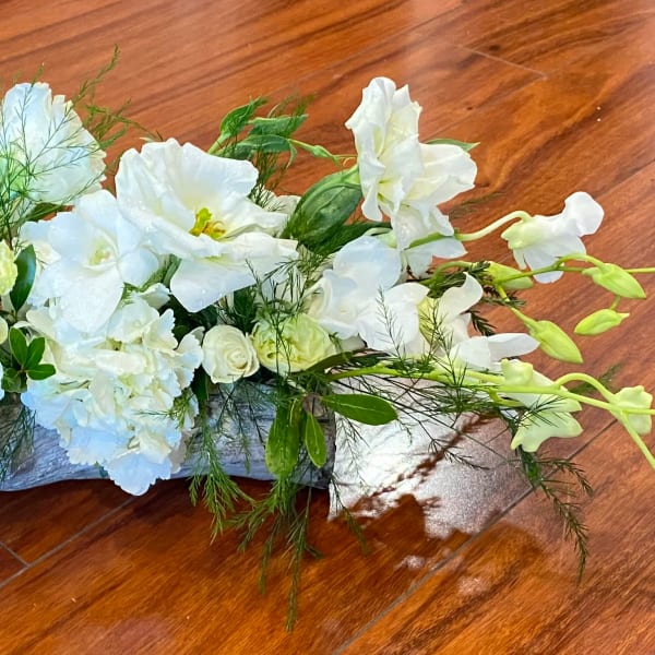 White floral centerpiece with orchids and roses on a low base
