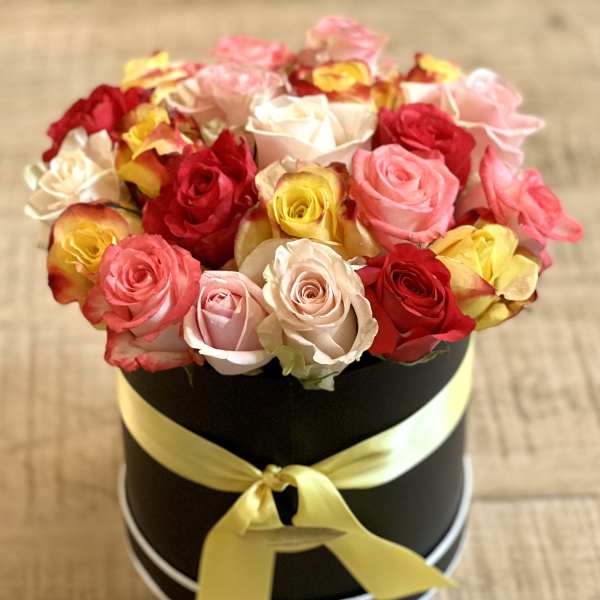 Round box of multicolored roses tied with a yellow ribbon