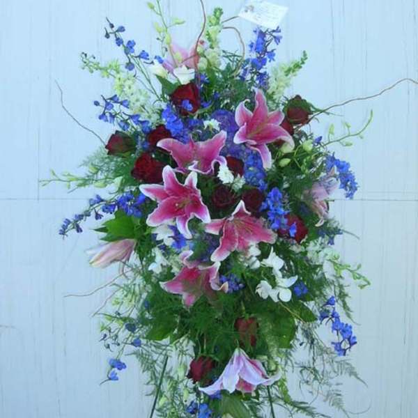 Tall floral spray with pink lilies, red roses, and blue flowers