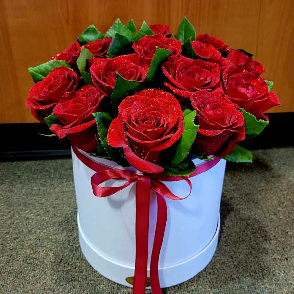 Red roses arranged in a white round box with a red ribbon