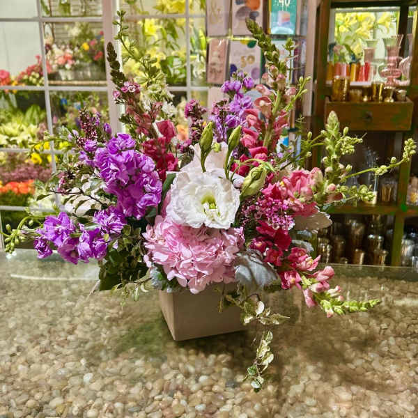 Pink, purple, and white flowers arranged in a square vase