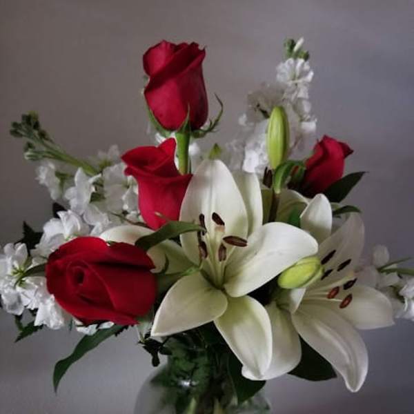 Red roses and white lilies arranged in a glass vase