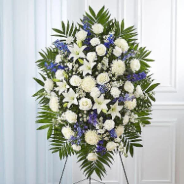 Standing funeral spray of white and blue flowers on an easel