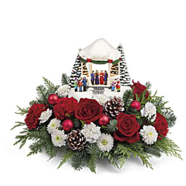 Christmas floral arrangement with red roses, white flowers, and a miniature winter village