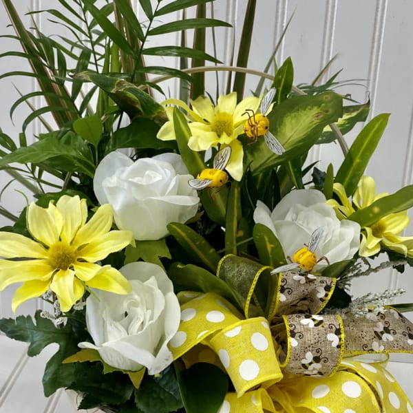 Basket arrangement with white roses, yellow daisies, and a large yellow ribbon