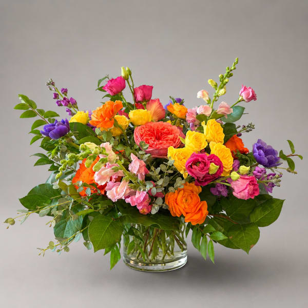 Colorful mixed bouquet in a clear glass vase with roses and snapdragons