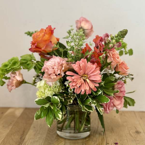 Mixed pink and orange flowers arranged in a clear glass vase
