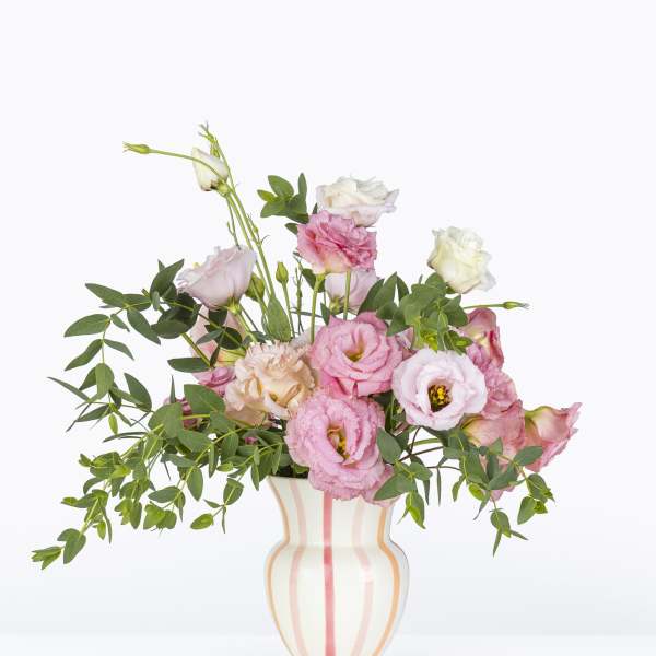 Pink and white lisianthus arranged in a striped vase