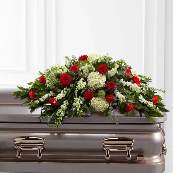 Red roses and white flowers arranged on a silver casket