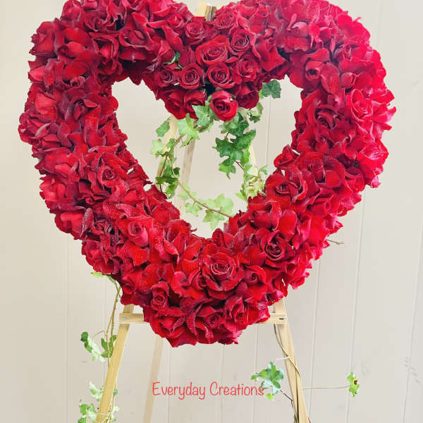 Heart-shaped red rose arrangement on a wooden easel
