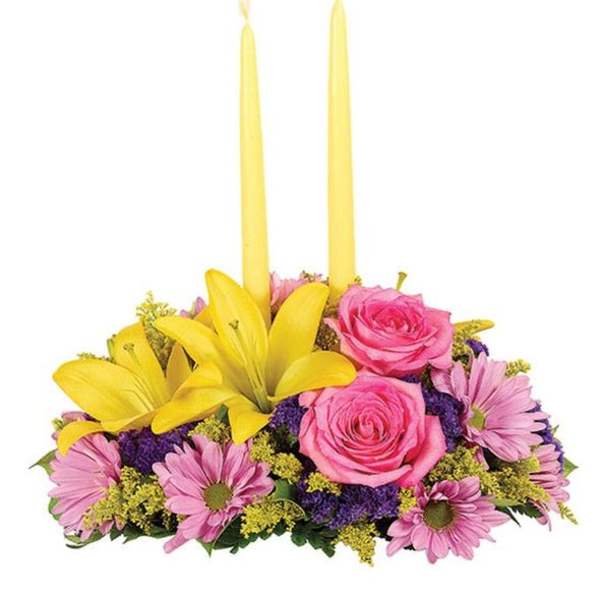 Pink roses and daisies arranged with two yellow taper candles